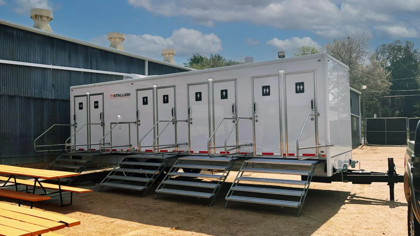 Ladies smiling and waving in front of portable toilets